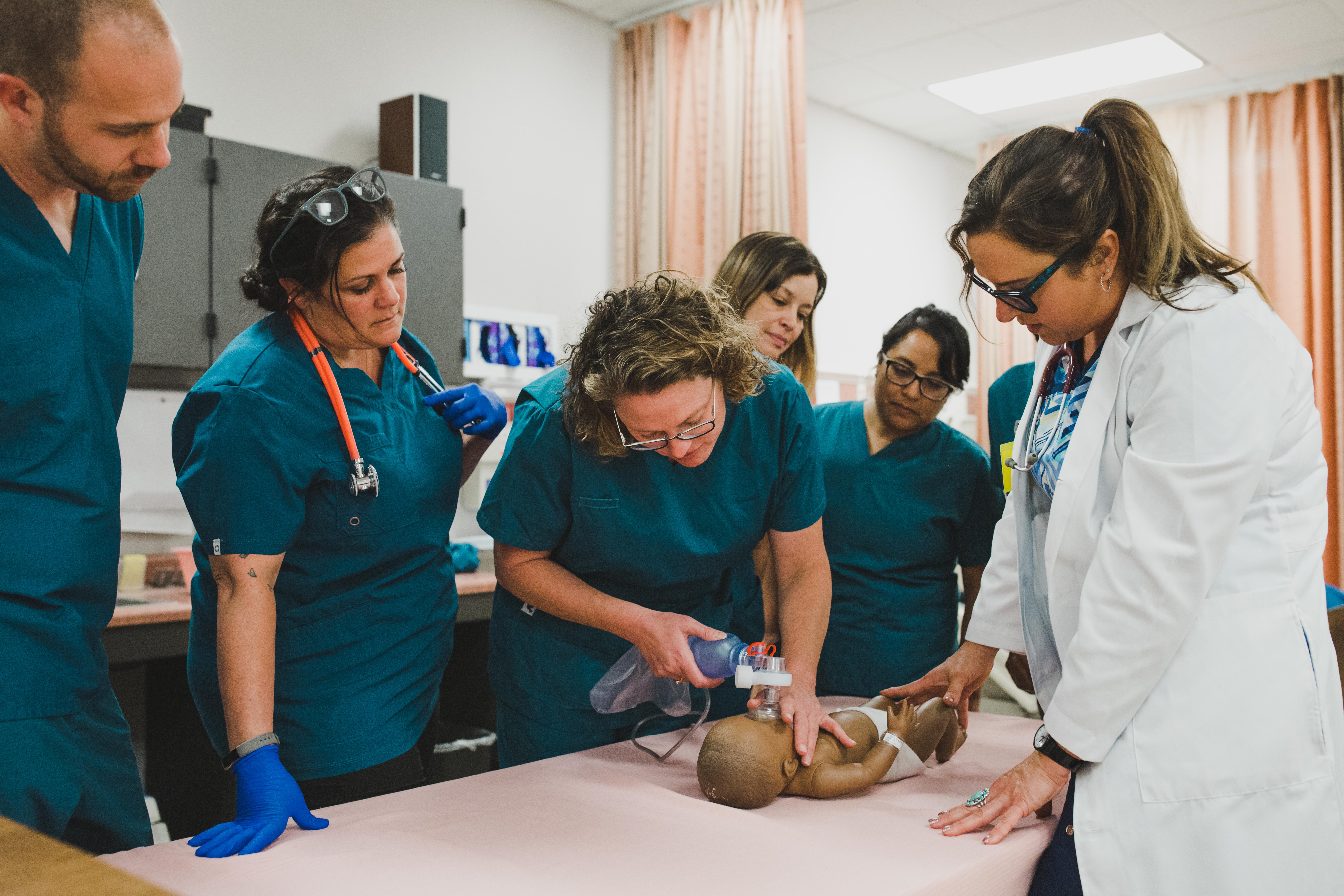 a group of nursing students surounds a CPR Manequin